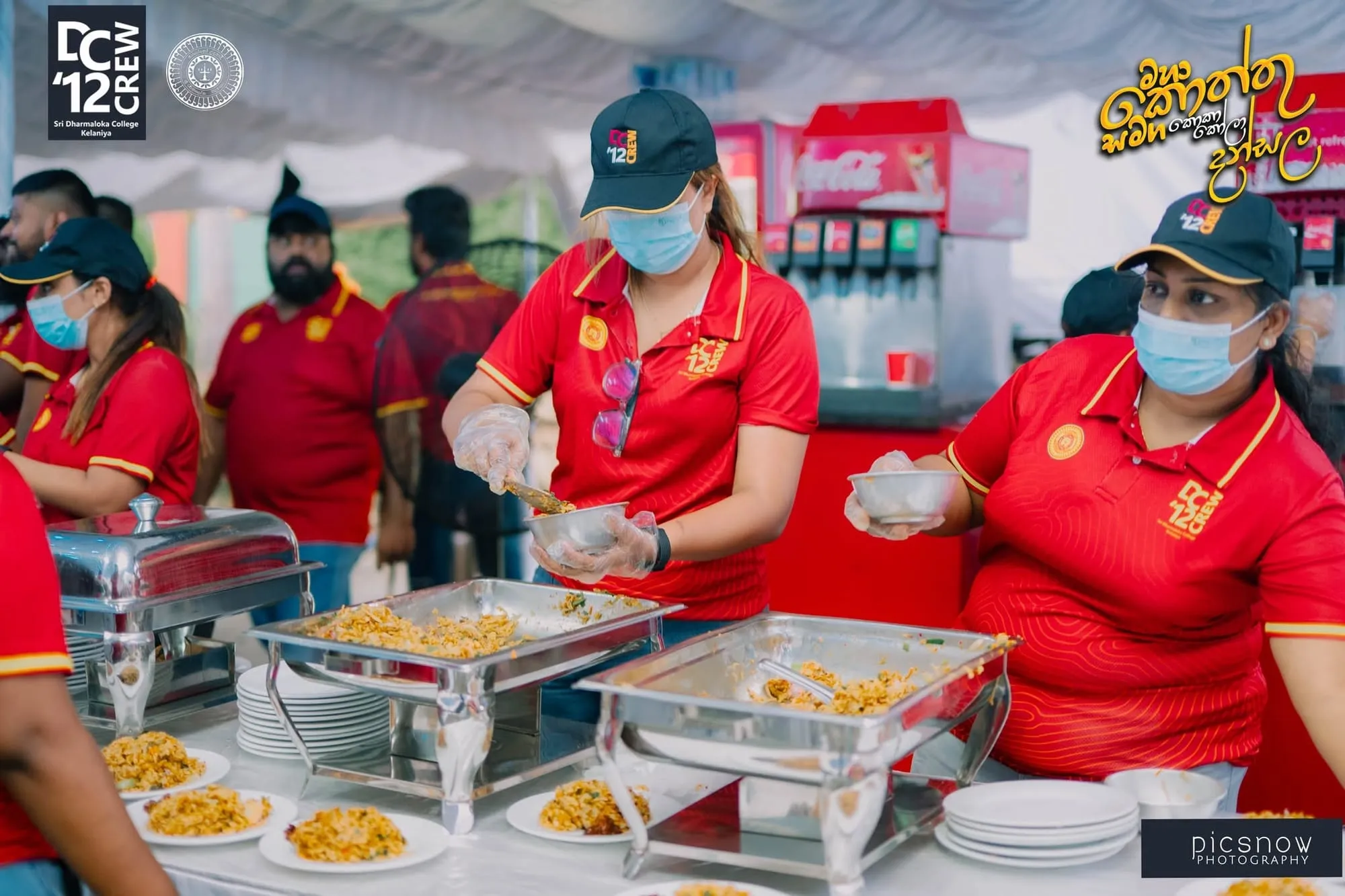 Volunteers plating kottu behind the serving counter at the Sri Dharmaloka College Kottu Dansala